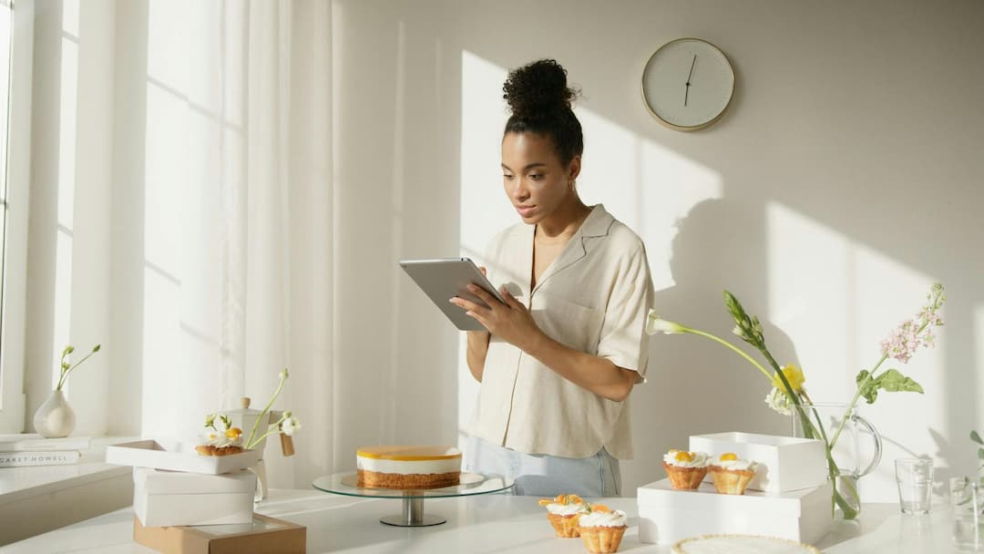 Woman in white shirt looking at iPad in bakery