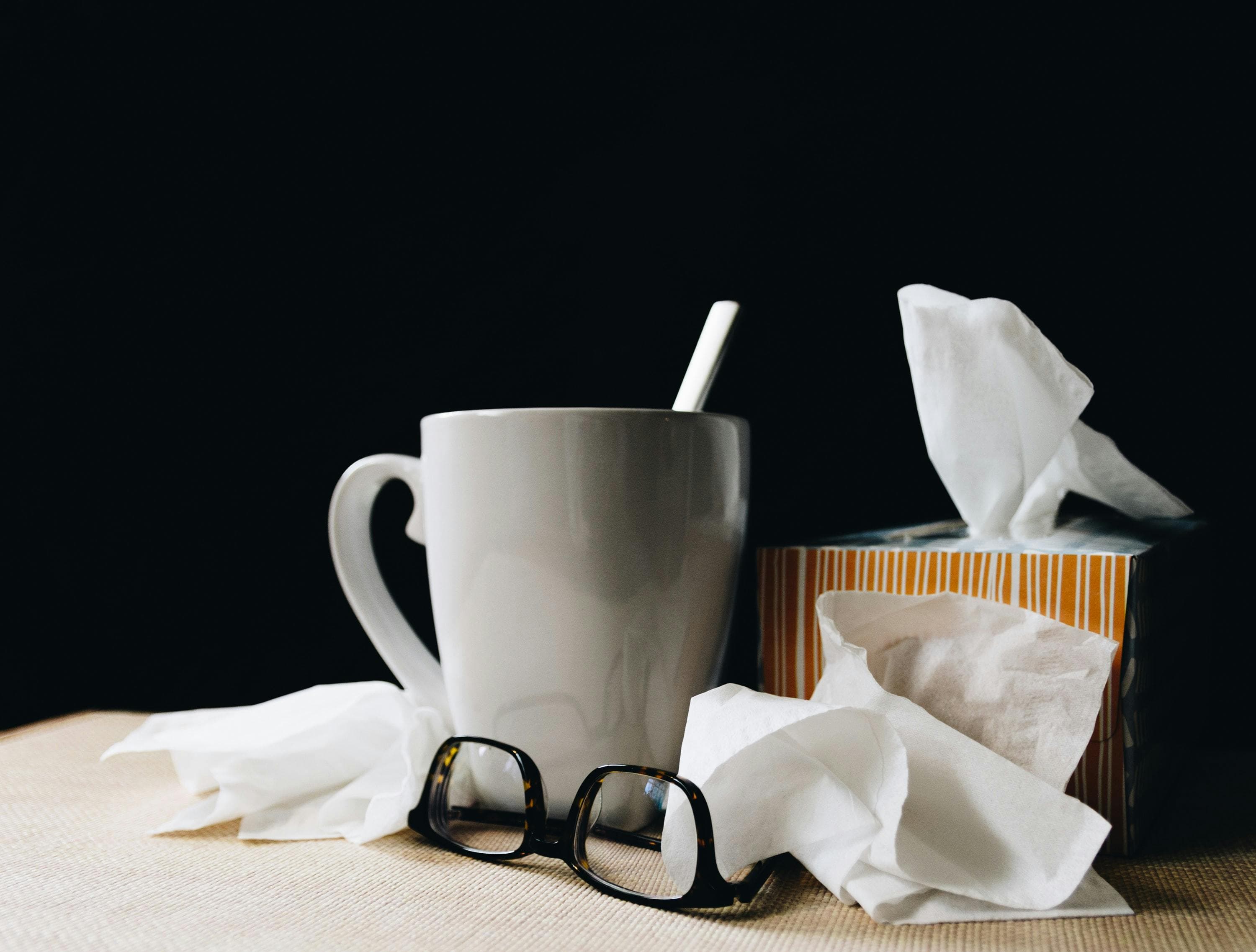 Coffee mug, glasses and tissues on a desk