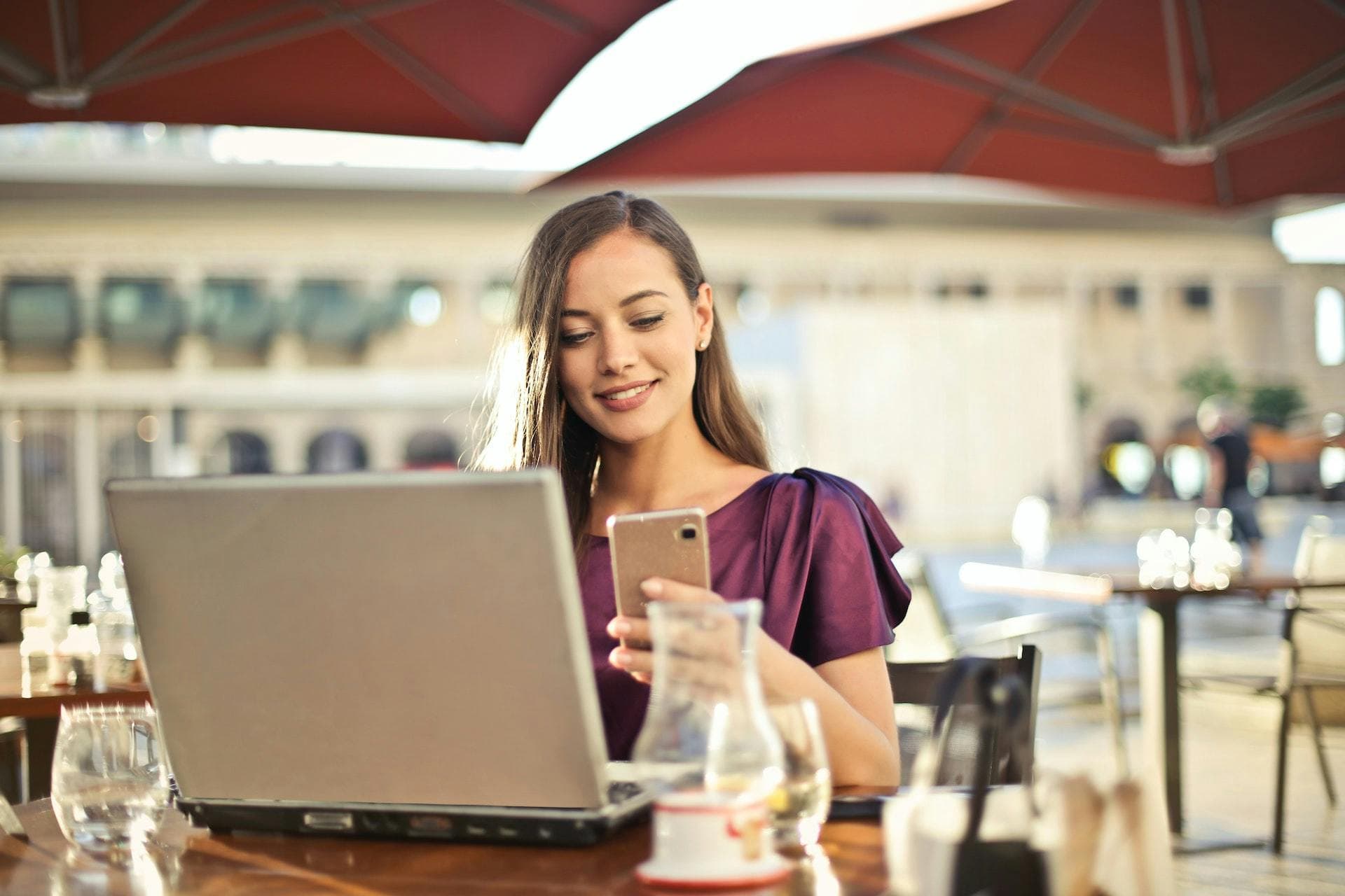 Female business owner on a laptop in a restaurant looking at her phone