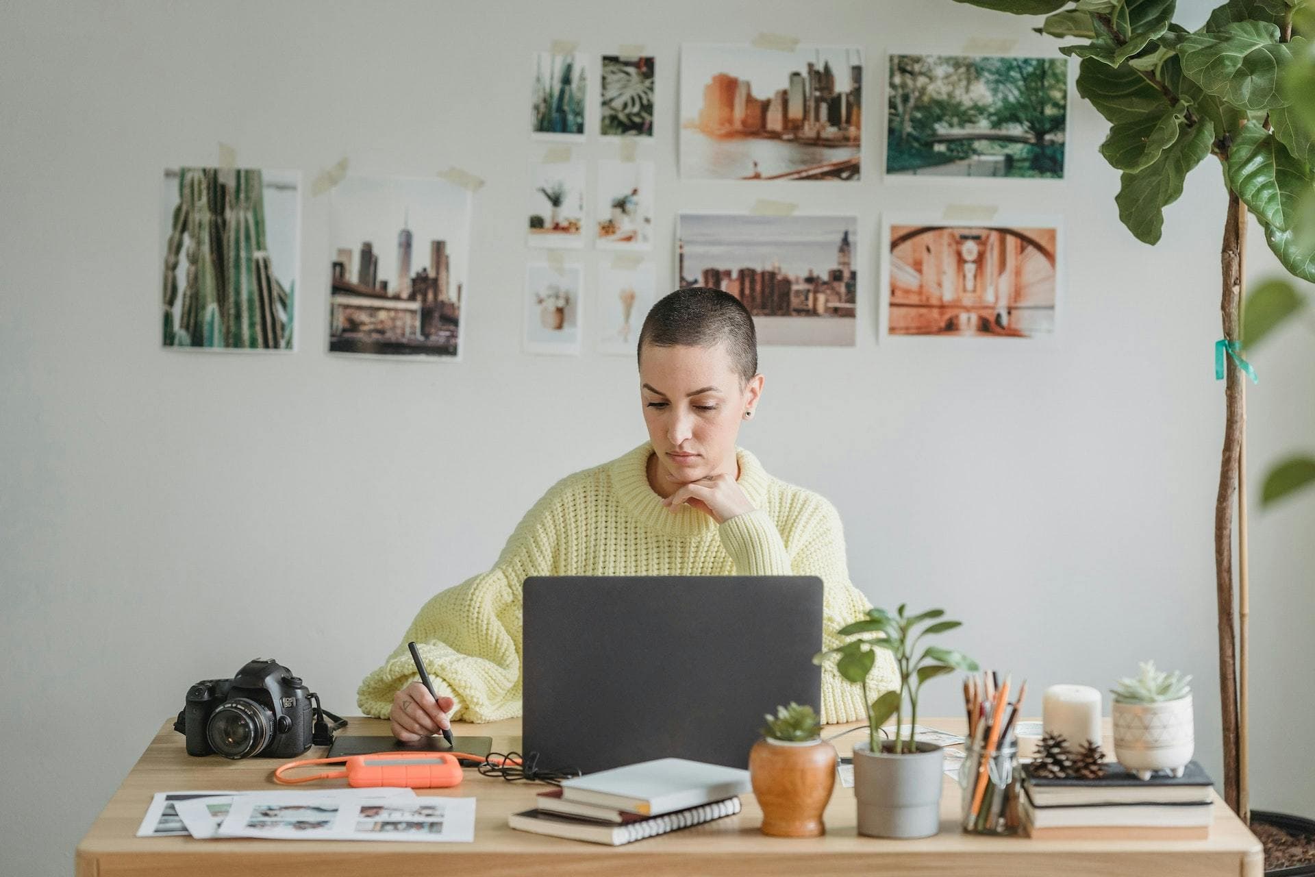 Female designer in a yellow jumper working in a white office in front of laptop
