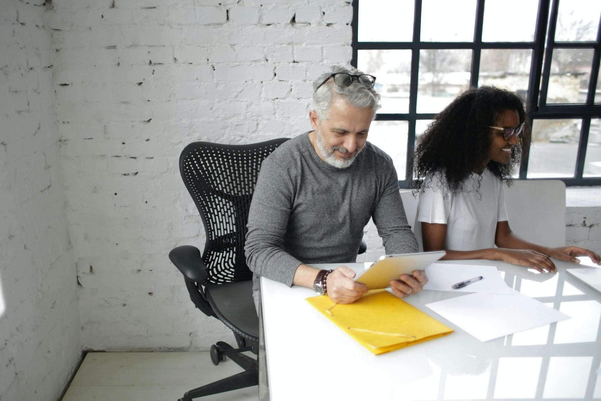 Two co-workers at a desk in a white office