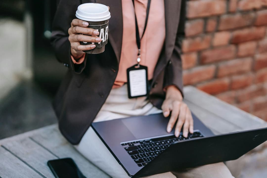 Cropped businesswoman on laptop holding a coffee
