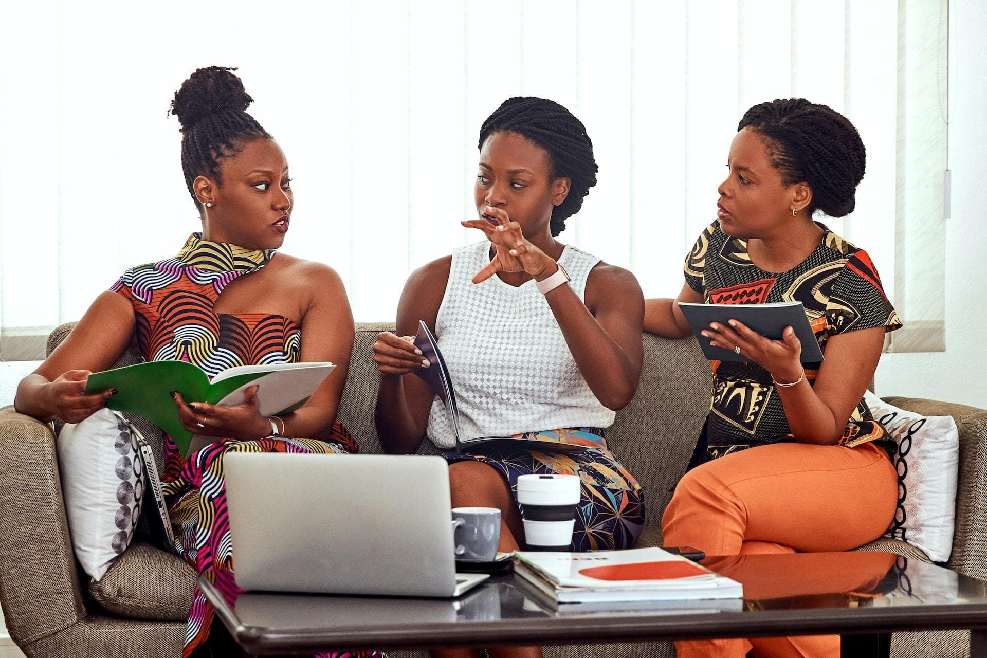 Three business women around a laptop talking to each other