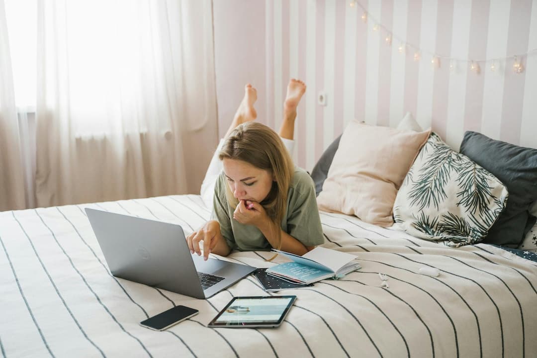Woman working on a laptop laying on a bed | Working from home tax relief: A guide for business owners