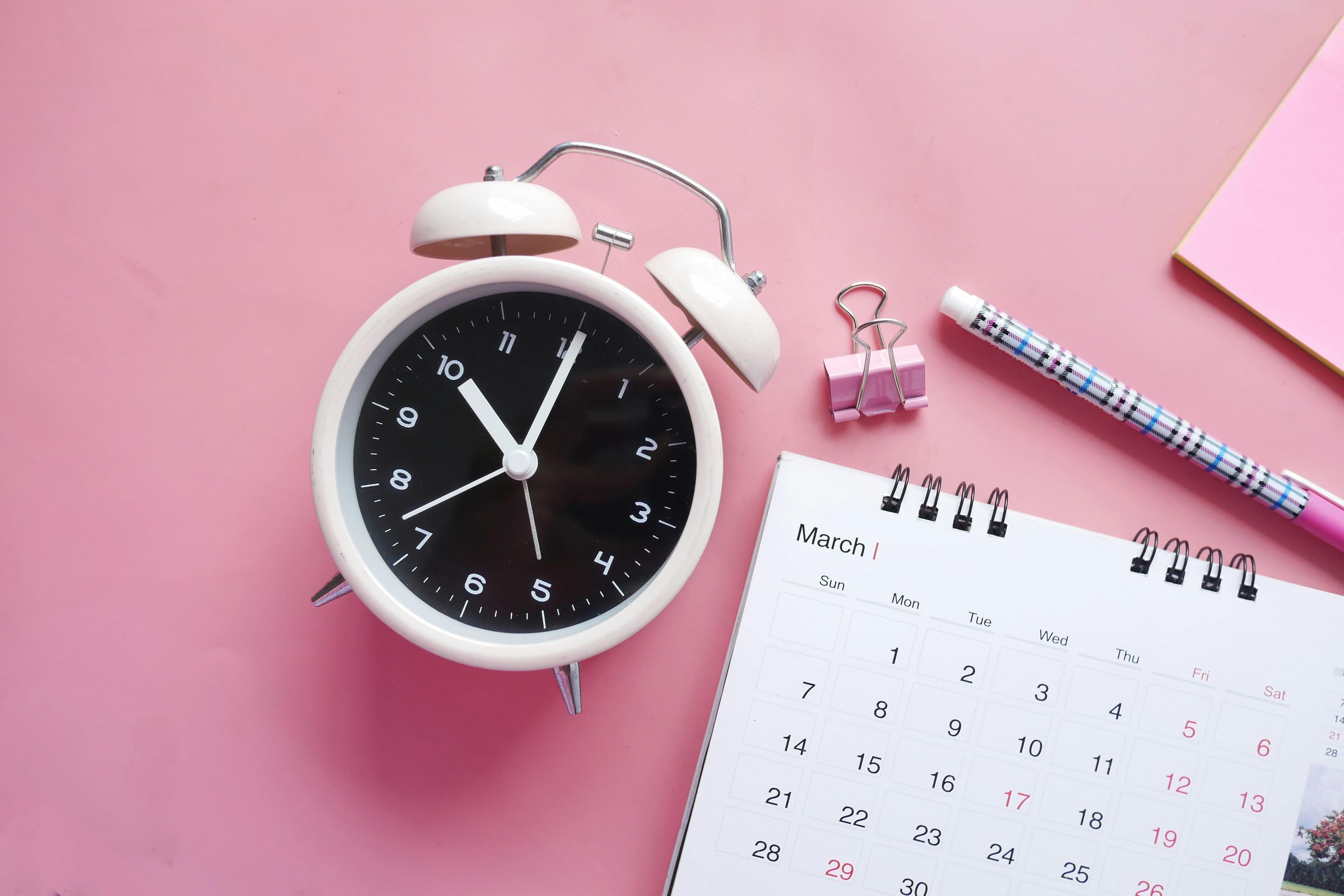 Clock and calendar on pink backdrop
