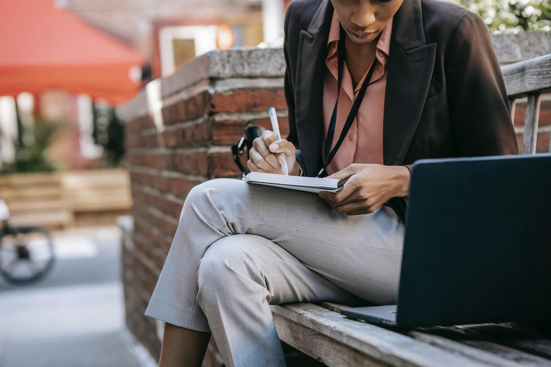 Business woman sat on a bench writing in a notebook